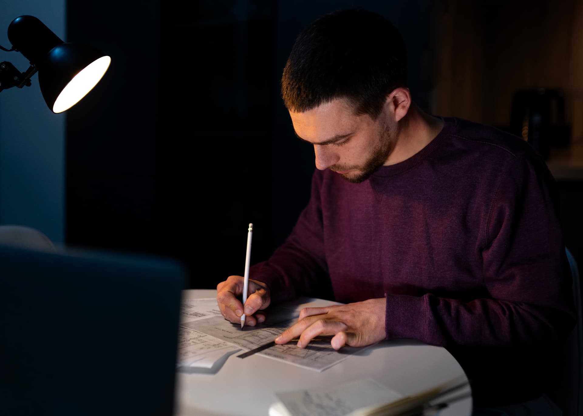Homem concentrado estudando à noite com luz de abajur